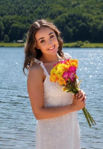 Jazmyne Brantley with a bouquet of flowers by a lake